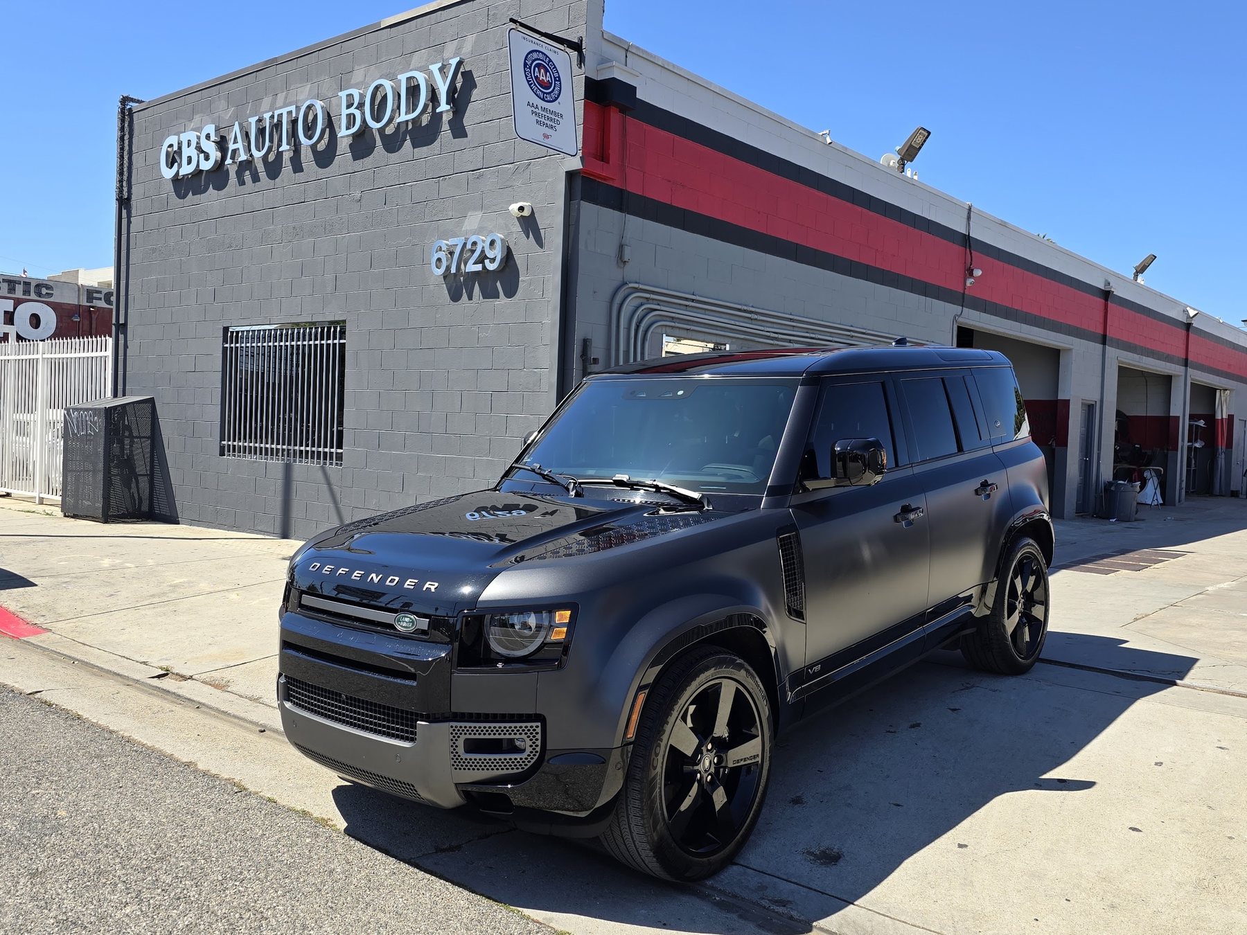 A matte-black Land Rover Defender outside the CBS Auto Body shop on Lankershim Boulevard